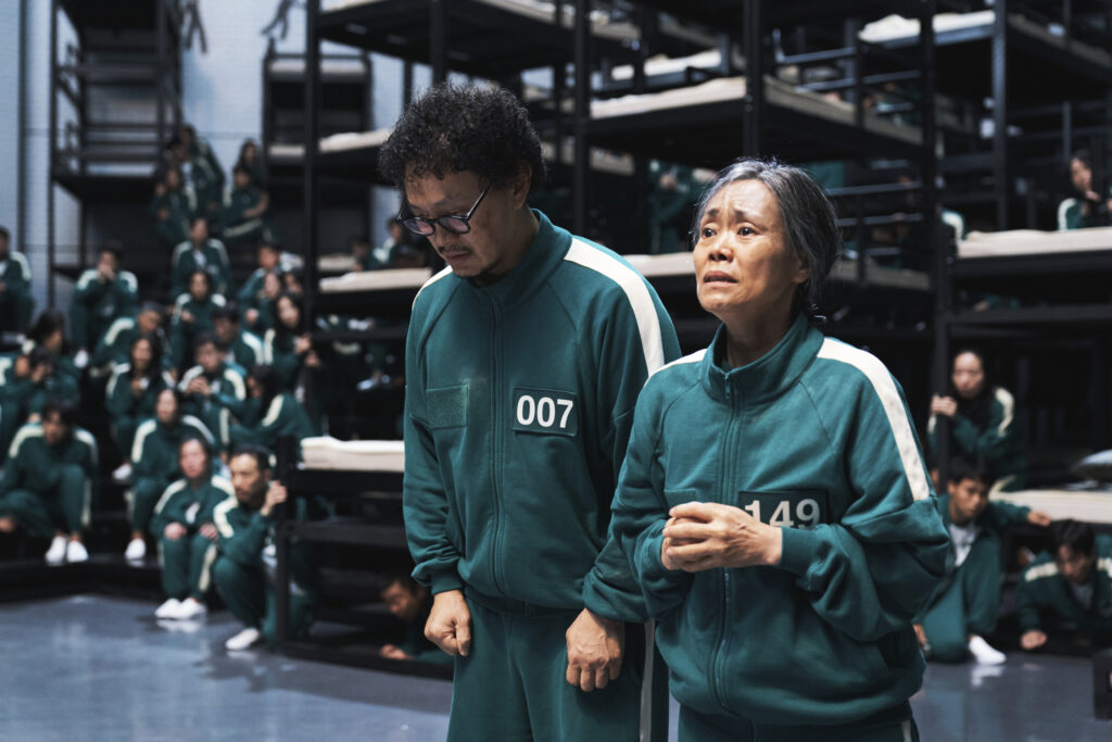 a man and woman in green tracksuits standing in a room with a group of people